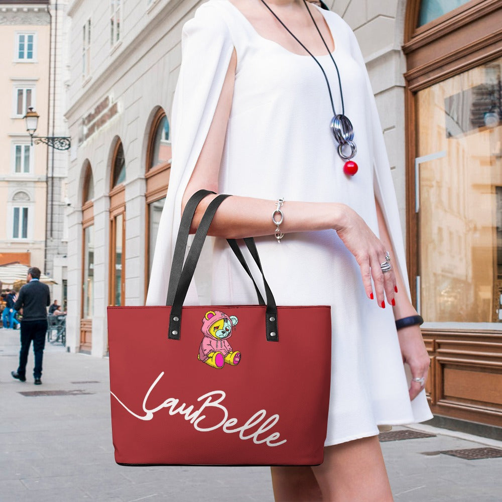 Woman in white dress holding red tote bag with a cute bear and "LauBelle" text, urban street.