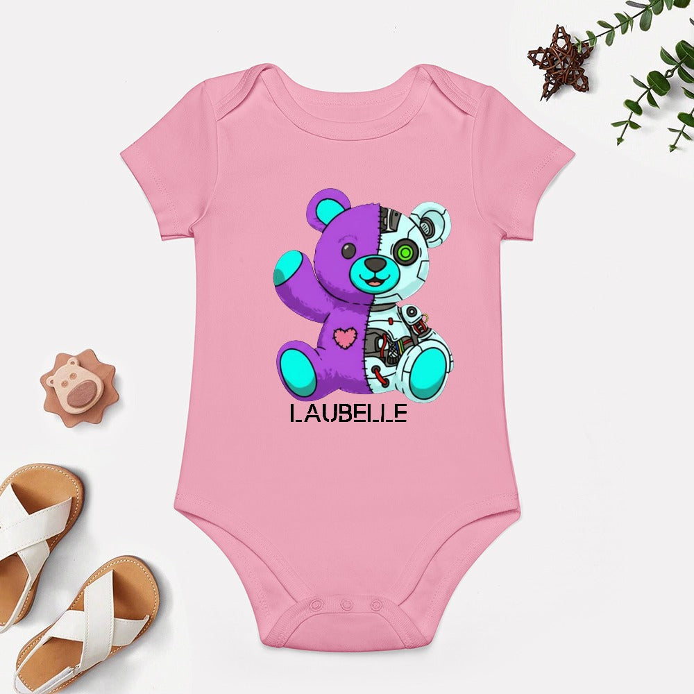 Pink baby onesie with half-purple, half-white teddy bear graphic, wooden shoes, and green plant.