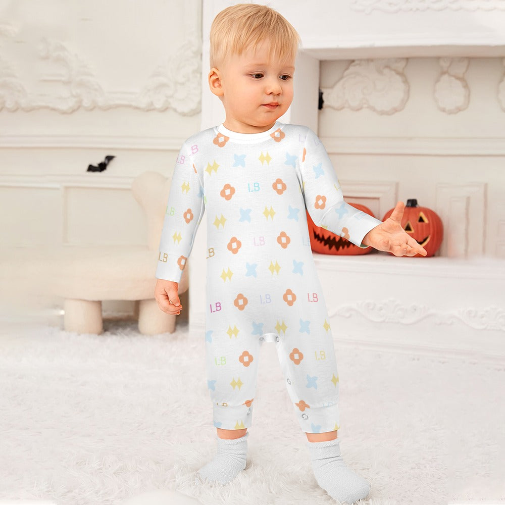 A toddler in a patterned white onesie stands on a white carpet, with a pumpkin decoration behind.