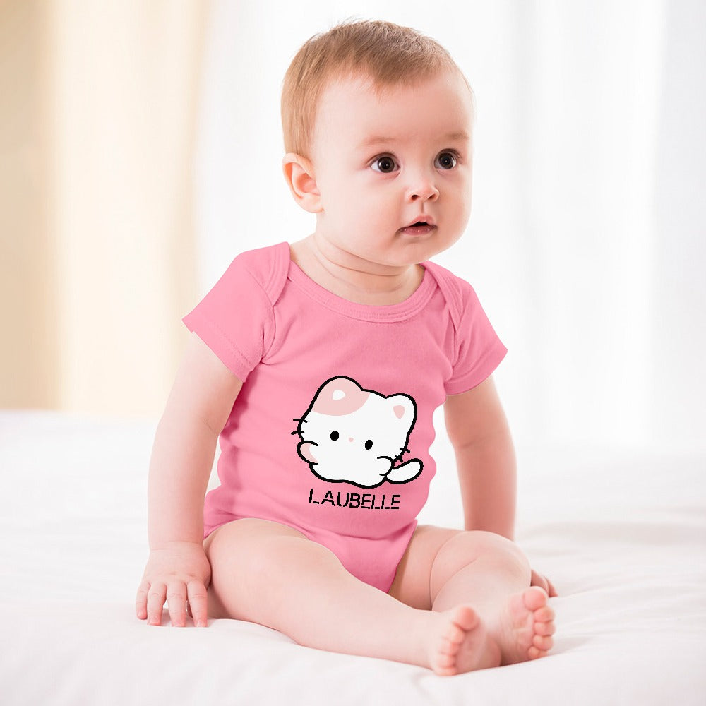 Baby in a pink onesie with a white cartoon cat design, sitting on a white surface.