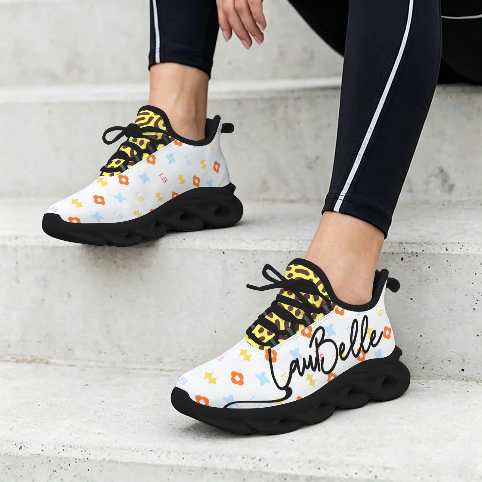 White sneakers with colorful patterns, black soles, and black laces, worn with black leggings.
