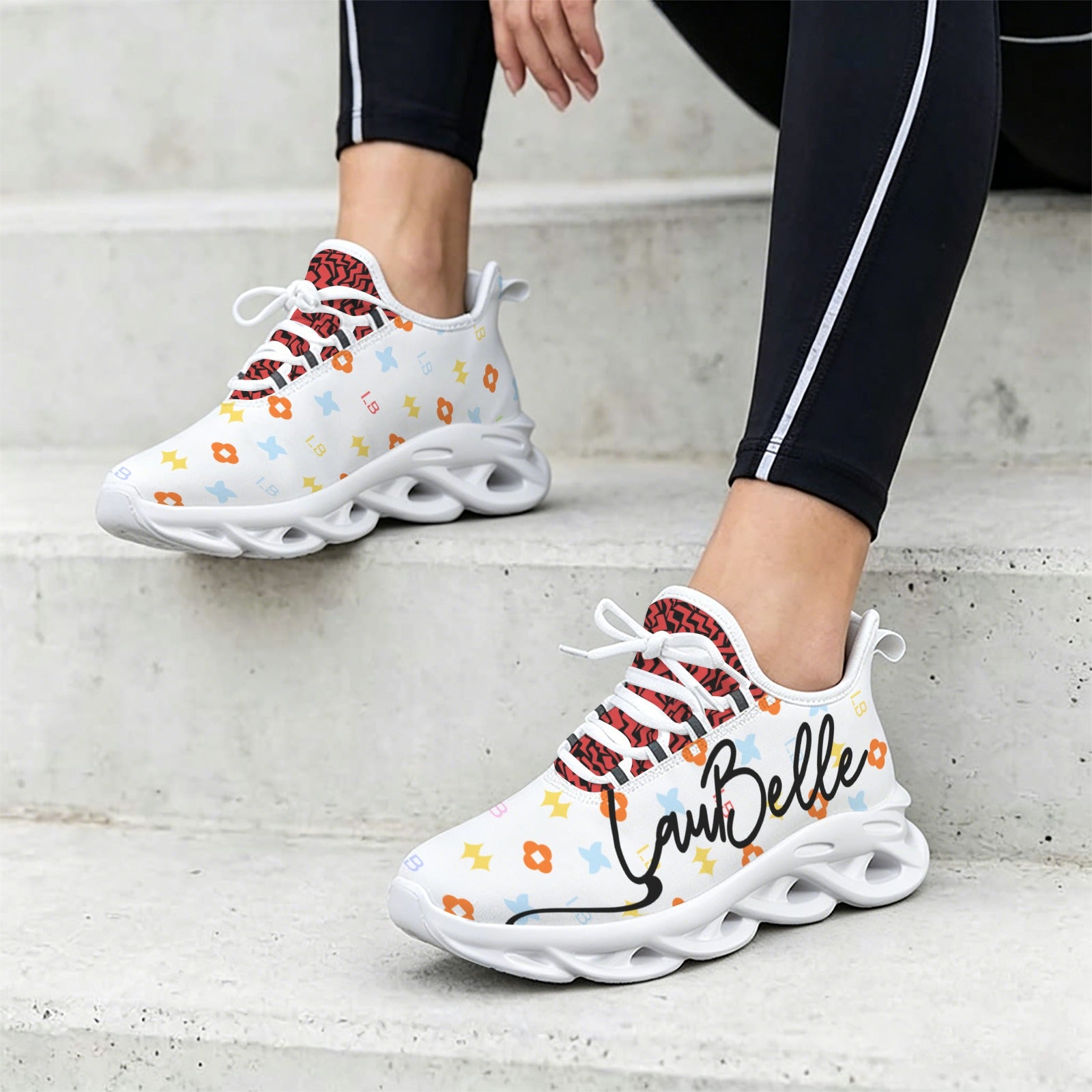 White sneakers with colorful patterns and "TamBelle" text, worn with black leggings on stairs.